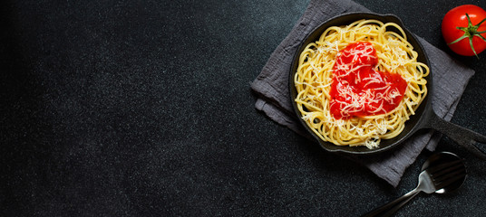 Spaghetti pasta with heart shaped tomato sauce, served in a pan. Dinner for Valentine's Day. Food with love. Top view, flat lay, black background
