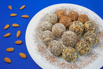 Vegetarian dates truffles in walnuts and almonds and in keroba on a blue background.