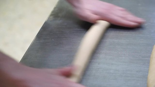 Relentless kneading dough manually on steel kitchen platform, closeup 