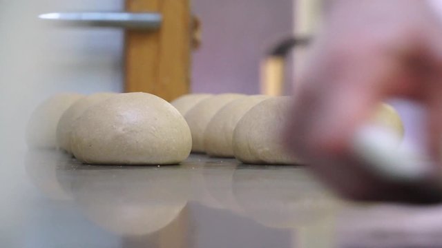 Kneading dough shaped balls and scraping extra on kitchen platform 
