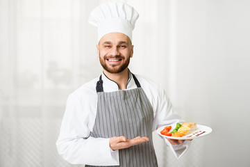 Chef Holding Plate With Roasted Salmon Steak Standing In Kitchen