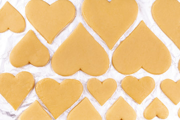 A Lot of Raw Homemade Heart Shaped Cookies Lie on Baking Foil and Prepare To Be Sent To Oven. Concept of Happy Valentines Day and Birthday. Top View