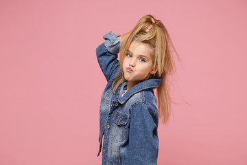 Pretty little blonde kid girl 12-13 years old in denim jacket isolated on pastel pink background...