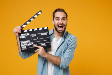Excited young man in casual blue shirt posing isolated on yellow orange wall background, studio...
