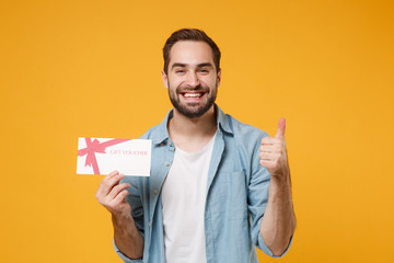 Smiling young man in casual blue shirt posing isolated on yellow orange wall background, studio...