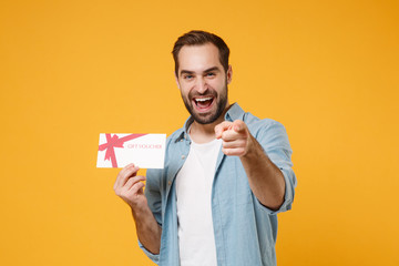 Laughing young man in casual blue shirt posing isolated on yellow orange background, studio...