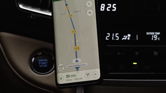Close up on screen navigation tracking vehicle location and route while driving on road. GPS navigation on smartphone showing route.