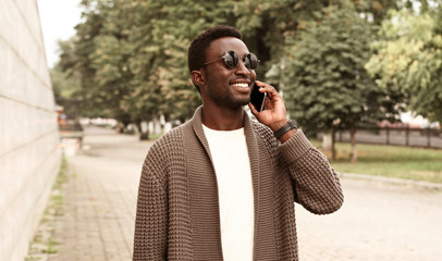 Portrait happy smiling african man calling on smartphone wearing brown knitted cardigan and...