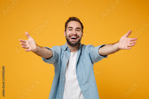 Cheerful Young Bearded Man In Casual Blue Shirt Posing Isolated On Yellow Orange Background Studio Portrait People Emotions Lifestyle Concept Mock Up Copy Space Standing With Outstretched Hands Wall Mural Vidi Studio Cheerful Young Bearded Man In Casual Blue Shirt Posing Isolated On Yellow Orange Background Studio Portrait People Emotions Lifestyle Concept Mock Up Copy Space Standing With Outstretched Hands Wall Mural Vidi Studio