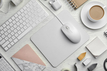 Flat lay composition with wired computer mouse, keyboard and stationery on white wooden table