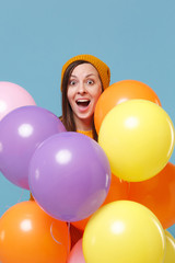 Fototapeta na wymiar Surprised young woman girl in sweater hat posing isolated on blue background studio portrait. Birthday holiday party people emotion concept. Mock up copy space. Celebrating hold colorful air balloons.