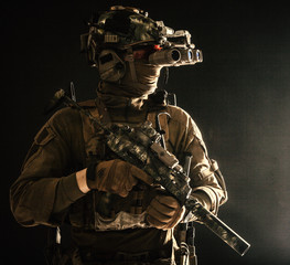 Army special forces tactical group fighter moving in darkness, using radio headset, looking through...