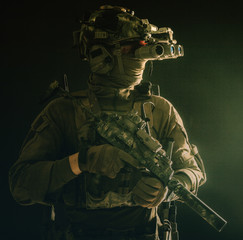 Army special forces tactical group fighter moving in darkness, using radio headset, looking through...