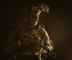 Army special forces tactical group fighter moving in darkness, using radio headset, looking through...