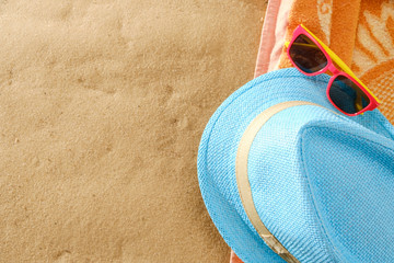 Top view of sandy beach with towel frame and summer accessories. Background with copy space and sand texture.