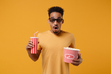 Shocked young african american guy in 3d imax glasses posing isolated on yellow orange background....