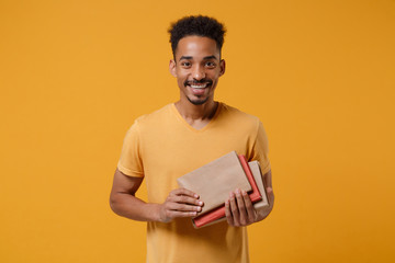 Joyful young african american guy in casual t-shirt posing isolated on yellow orange wall...