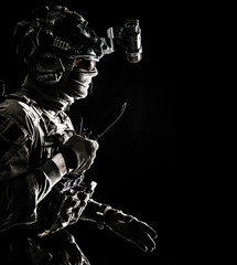 Fototapeta na wymiar Army elite commando, professional mercenary, counter-terrorist tactical team fighter in combat helmet, equipped night-vision device, creeping in darkness with service knife in hand, studio shoot
