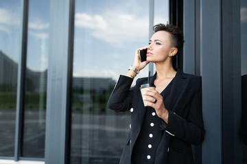 attractive business woman talking on the phone against the background of the entrance at the office building