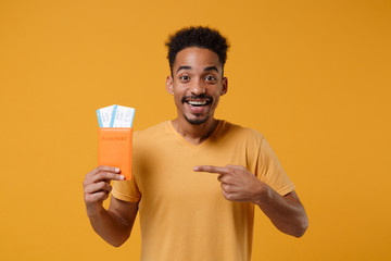 Excited young african american guy in casual t-shirt posing isolated on yellow orange background....