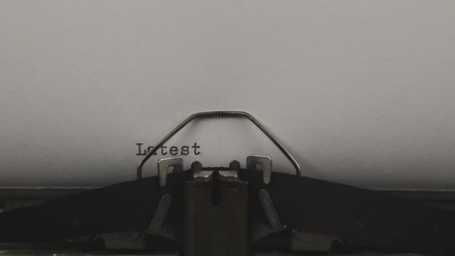 close-up typing a quote latest news, old vintage typewriter with a sheet of paper