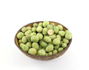 Peanuts in a wasabi coating inside a coconut  shell on white background