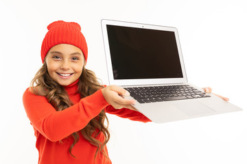 Happy caucasian girl in red hat and hoody shows a laptop isolated on white background