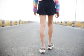 Young woman walking on the road with white sky background.