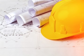 Yellow hard hat and blueprints in a construction paper