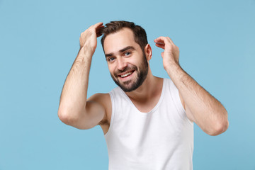 Close up bearded young man 20s years old examining his hair in white shirt isolated on blue pastel...