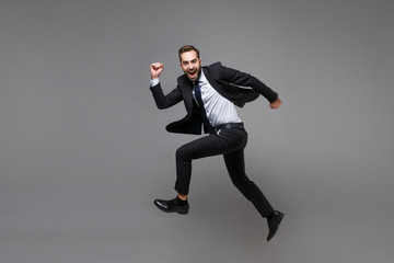 Side view of funny young business man in classic suit shirt tie posing isolated on grey background....
