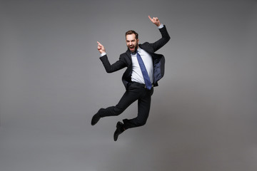 Happy young business man in classic black suit shirt tie posing isolated on grey background....