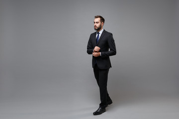 Successful young bearded business man in classic black suit shirt tie posing isolated on grey...