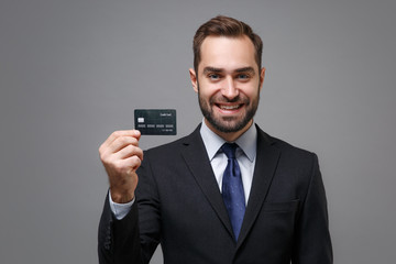 Smiling young business man in classic black suit shirt tie posing isolated on grey wall background...