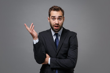 Perplexed irritated young bearded business man in classic black suit shirt tie posing isolated on...