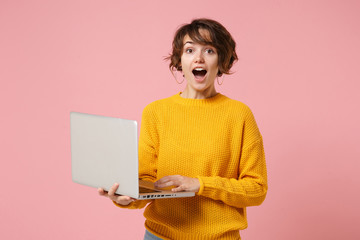 Shocked young brunette woman girl in yellow sweater posing isolated on pastel pink background...