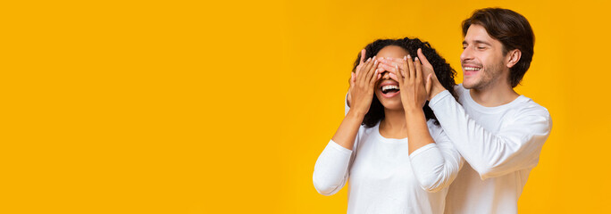 Loving boyfriend covering his girlfriend's eyes from behind making romantic surprise