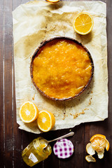 Tangerine citron tart on a rustic background with a vase of tangerine jam, top view, natural light