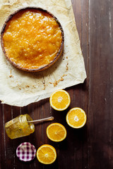 Tangerine citron tart on a rustic background with a vase of tangerine jam, top view, natural light