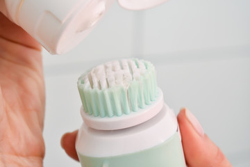 Girl is cleaning face with electric brush. Woman with special brush for deep cleansing facial remove makeup. Skin Care concept. High technology beauty.