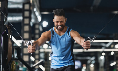 Bodybuilder training with block exerciser at gym