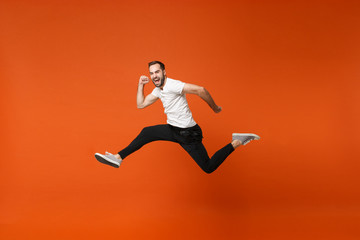 Cheerful crazy young man in casual white t-shirt posing isolated on bright orange wall background...