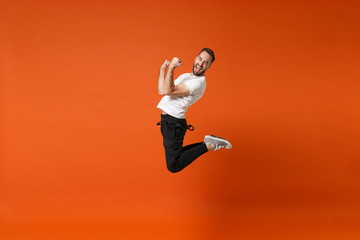 Happy joyful young man in casual white t-shirt posing isolated on bright orange wall background...