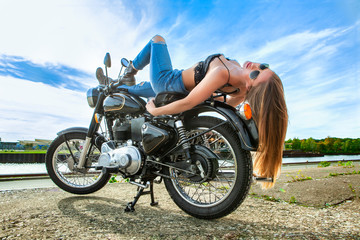 An attractive girl on a motorbike posing outside