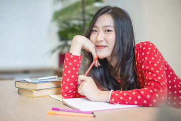 Young beautiful Asian woman reading a book while doing her homework in the modern co working space	
