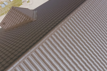 Brown metal tile on the roof of the house. Corrugated metal roof