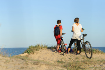 boy and young woman on a Bicycle on a cliff by the sea