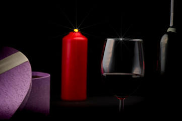 Red wine bottle, glass of wine, candle and gift box
