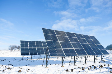 Solar panels in winter sunny morning on a snowy field in Ukraine. Green energy concept in the...