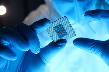 Male hand in blue protective gloves hold micro rocessor closeup. Protecting flash memory storage...